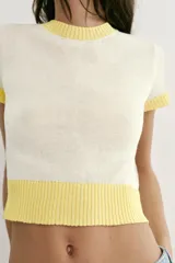 Top de punto color crudo con cuello redondo, manga corta y detalles de rib en color amarillo en el cuello, los puños y el ruedo.