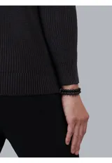 Sweater de punto en color beige, con cuello alto y cierre frontal parcial. Diseño de manga larga con puños y ruedo acanalados.