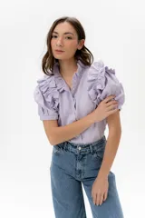 Camisa celeste de lino con cuello mao y mangas cortas abullonadas con volados. Cierre frontal con botones.