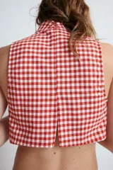 Top crop de cuello alto y sin mangas, con estampado de cuadros vichy en color rojo y blanco, y cierre de cremallera oculta en la espalda.