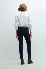 Pantalón de denim negro, corte slim, con cintura media y cierre frontal con botón y cremallera.