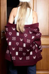 Campera tejida en jacquard color bordó con diseño gráfico de tableros. Presenta cuello polo, cierre frontal doble y mangas largas.