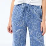 Pantalón de corte recto y holgado, confeccionado en lino azul con estampado de flores lineales en color blanco. Presenta cintura elástica con cordón de ajuste y bolsillos laterales.