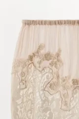 Shorts de tiro bajo con cintura elástica, confeccionados en tejido georgette de viscosa. Presentan un diseño delicado con bordados florales y aplicaciones de encaje a contraste en el ruedo.