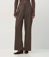 Pantalón de vestir estilo sastre con corte wide leg, confeccionado en tejido crepé color marrón con sutil estampado de rayas verticales. Presenta pliegues delanteros, cintura estructurada con trabillas y cierre frontal.