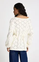 Sweater de punto color blanco con diseño geométrico calado. Presenta un amplio escote barco, mangas largas con volumen sutil y cintura ajustable mediante lazo frontal con terminaciones metálicas. Los puños y el bajo son acanalados.