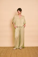 Pantalón palazzo de satén color verde, de tiro alto y corte amplio con bolsillos laterales.