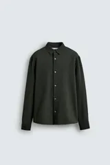 Camisa de corte regular fit confeccionada en tejido de algodón con textura de cuadrillé. Presenta cuello solapa, manga larga con puños abotonados y cierre frontal mediante botonadura.