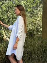Vestido camisero color beige claro, de lino 100% natural, con botones de nácar, bolsillo delantero y mangas 3/4 con botón para recogerlas. Diseño asimétrico, más largo en la parte trasera.