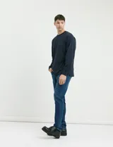 Pantalón de jean de corte recto slim, con diseño clásico de cinco bolsillos y cierre frontal con botón y cremallera.