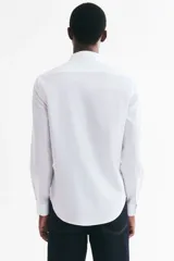 Camisa de algodón blanca con cuello italiano, cierre frontal de botones y mangas largas con puños ajustables. Corte entallado Slim Fit.