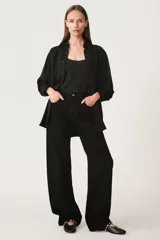 Pantalón de jean negro de corte ancho, tiro alto, con cinco bolsillos y cierre frontal con cremallera y botón metálico.