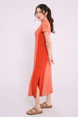 Vestido midi de corte recto y diseño bicolor, con frente en color crema y laterales en color beige. Presenta cuello redondo, mangas cortas y aberturas laterales en el ruedo.