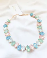 Gargantilla dorada con cristales facetados en forma de gota en tonos pastel: rosa, celeste, verde y blanco.