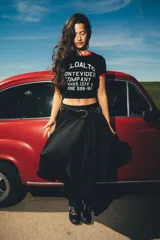 Remera tipo baby tee negra con ribetes rojos en cuello y mangas, y estampa frontal blanca con texto de marca y diseño de estilo vintage.
