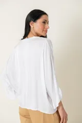 Blusa italiana de viscosa color beige, de calce holgado, con escote en V y detalle de lurex. Presenta mangas tres cuartos y diseño fluido.
