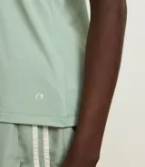 Musculosa deportiva de corte nadador, color amarillo claro, confeccionada en microfibra con textura perforada. Presenta escote en U y diseño holgado con pliegue en la espalda.