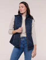 Chaleco acolchado azul marino con diseño capitoneado en rombos, cuello alto y detalles de ribete marrón en el cierre frontal y hombros. Cuenta con paneles laterales elásticos y bolsillos con cierre.