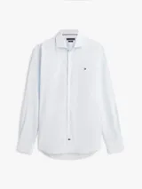 Camisa de Tommy Hilfiger confeccionada en popelín de puro algodón regenerativo con diseño de rayas bengal en tonos celeste y blanco. Cuenta con cuello camisero, cierre frontal de botones y el logo de la marca bordado en el pecho.
