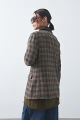 Blazer de corte relajado con estampado de cuadros tipo pied de poule en tonos rojizos y verdes. Presenta solapas clásicas en color azul oscuro y estructura definida.