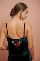 Top verde oscuro de terciopelo con breteles finos y escote en V. Presenta una flor bordada en la espalda.