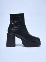 Bota corta negra con textura símil cuero de cocodrilo, caña media, punta cuadrada, plataforma delantera y taco geométrico.
