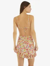 Minifalda de playa con estampado floral multicolor, con volantes en el ruedo y cierre frontal con nudo.