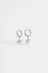 Aros de acero quirúrgico plateado tipo argolla con dije colgante en forma de estrella de ocho puntas que incluye un strass en el centro.