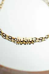 Pulsera dorada de acero quirúrgico con baño de oro 18k y cadena de eslabones ovalados. Dije con la palabra “mamá”.