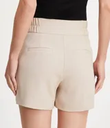 Bermuda roja de poliéster con cintura elástica, bolsillos laterales y cierre con cremallera y botones.