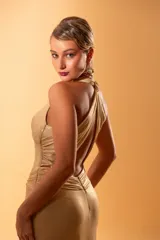 Vestido largo de fiesta dorado con escote halter y espalda cruzada. Drapeado en la cintura con broche de strass.