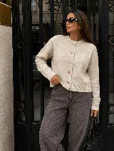 Cardigan negro de tejido de punto con cuello redondo, manga larga y cierre frontal de botones dorados metálicos grabados.
