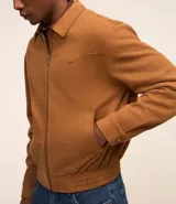 Campera masculina de estilo casual con cuello inglés, cierre frontal por cremallera, bolsillos laterales y ajuste elástico en el bajo. Presenta detalles de recortes en la parte superior delantera.
