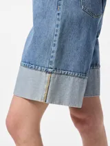 Bermuda de denim celeste, de tiro medio, calce suelto y ruedo doblado.