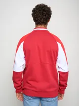 Campera tipo bomber de felpa, color rojo con detalles en blanco en las mangas y cuello. Presenta cierre frontal completo, logo de Umbro y escudo del Club Nacional de Football bordados en el pecho.