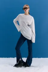 Remerón de manga larga y corte holgado, color blanco, con estampa serigráfica en la espalda que incluye motivos orientales como una rama de flores, un pez koi, una mariposa y texto en japonés. Presenta un parche decorativo en la parte inferior.