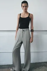 Pantalón de tiro medio con corte flare y pernera ancha. Presenta cintura con trabillas, bolsillos laterales, raya planchada frontal y cierre con cremallera, botón y ganchos metálicos.