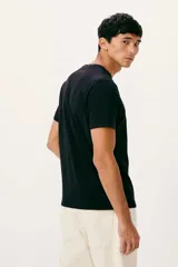 Remera beige de manga corta con cuello redondo, confeccionada en tejido de algodón. Presenta un pequeño estampado en el pecho con diseño de una bandera y el texto "H R NG est. 1880".