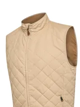 Chaleco acolchado color beige con diseño de pespuntes en rombo, cierre frontal completo y cuello alto. Cuenta con bolsillos laterales con cierre y un tirador de cierre con detalle en cuero.
