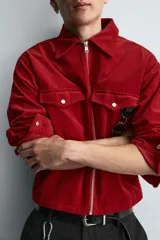 Sobrecamisa de corte boxy fit confeccionada en tejido de pana de algodón con elasticidad. Presenta cuello solapa, cierre frontal con cremallera, mangas largas con puños abotonados y dos bolsillos de plastrón con solapa en el pecho.