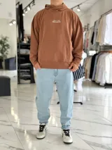 Canguro oversize color beige, con capucha y amplio estampado tipográfico en la espalda.