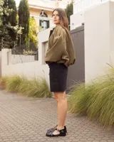 Sandalias de cuero negro charolado estilo romano, con tiras entrelazadas, tira en T y hebilla metálica de ajuste lateral.