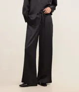 Pantalón wide leg de cintura alta, confeccionado en tejido satinado color negro, con elástico y lazo en la cintura y bolsillos delanteros.
