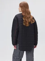 Campera reversible capitoneada con cierre frontal. Un lado es de color negro y el otro es de color beige, ambos con diseño acolchado. Cuenta con cuello redondo, mangas largas y bolsillos laterales.