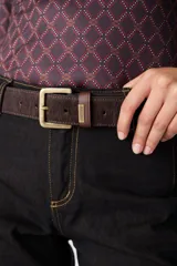 Cinturón de cuero vacuno con textura de pelo, color marrón oscuro, con hebilla metálica de acabado envejecido y pasador con placa metálica grabada con la marca.