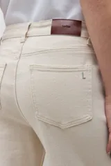 Jean de corte wide leg en color beige claro, con tiro medio y cierre frontal con botón y cremallera. Presenta un diseño de cinco bolsillos y costuras reforzadas.