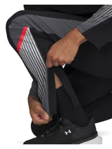 Pantalón deportivo Under Armour, modelo Velociti Storm, de color negro con paneles laterales en gris y detalles en rojo. Presenta un diseño ergonómico con pinzas en las rodillas, cintura elástica con cordón interno, bolsillos laterales y cremalleras en los tobillos.
