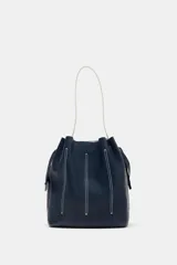 Bolso de hombro tipo saco confeccionado en piel azul marino, con detalle de pespuntes blancos verticales, asas finas de hombro en color blanco y cierre fruncido.