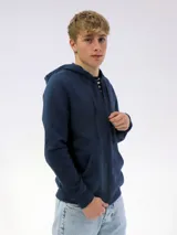 Campera deportiva unisex color beige, confeccionada en algodón con felpa, con capucha, cierre frontal y bolsillo tipo canguro.