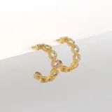 Par de aros tipo argolla abiertos, dorados, con textura acanalada y circonias engarzadas. Cierre a presión.